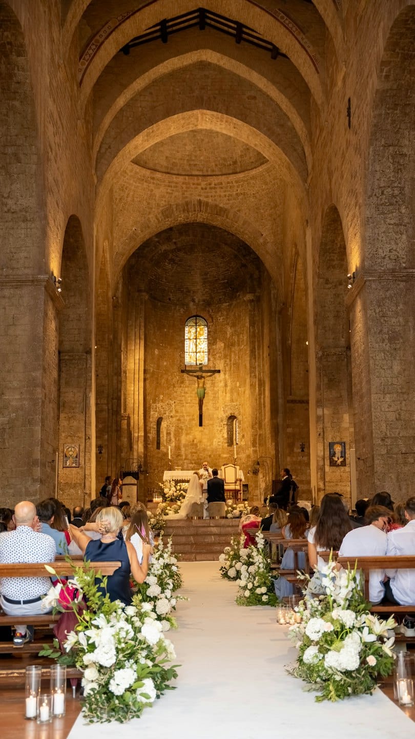 Coppia in ginocchio sull'altare durante la cerimonia nuziale in una chiesa di pietra.