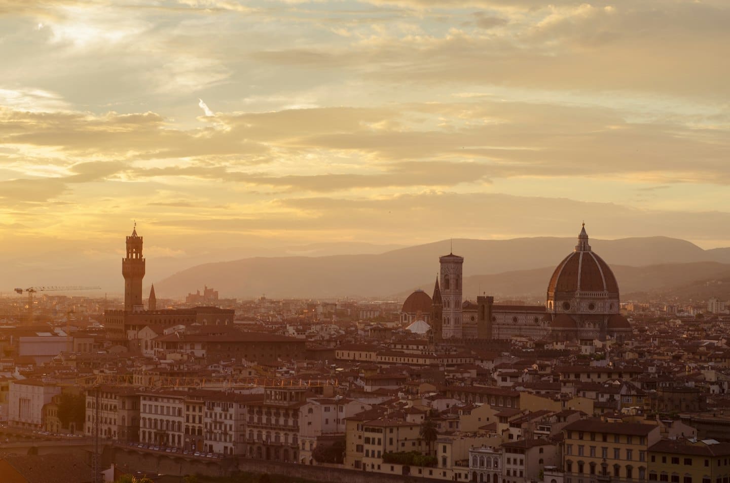 Tetti in terracotta e monumenti storici in un paesaggio urbano al tramonto.